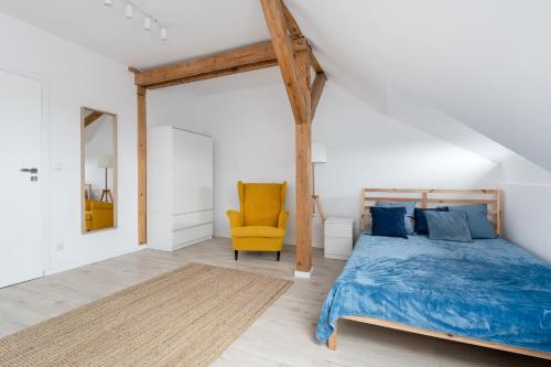 ein Schlafzimmer mit einem Bett und einem gelben Stuhl in der Unterkunft Quadra Rooms by 3City Rentals in Gdynia