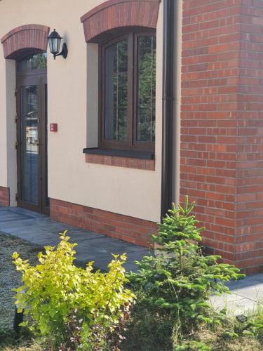 a brick building with a door and some bushes at Spalskie Pokoje Gościnne in Spała