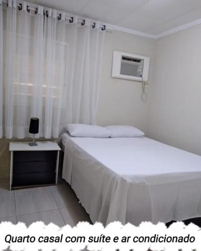 a white bedroom with a bed and a window at Veraneio Dona Rosa in Piranhas
