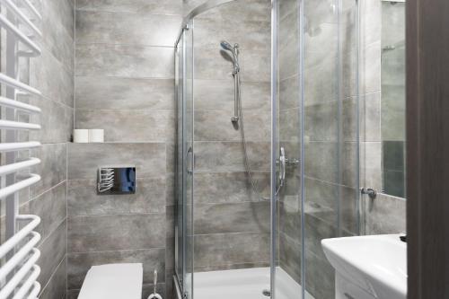 een badkamer met een douche, een toilet en een wastafel bij Spalskie Pokoje Gościnne in Spała