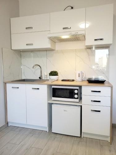 a white kitchen with a sink and a microwave at Mini Apartamenty Poznań in Poznań