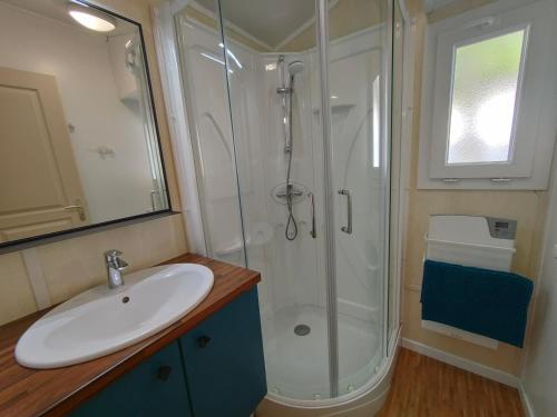 La salle de bains est pourvue d'une douche et d'un lavabo blanc. dans l'établissement Bungalow cosy à 300m de l’océan, à Bretignolles-sur-Mer
