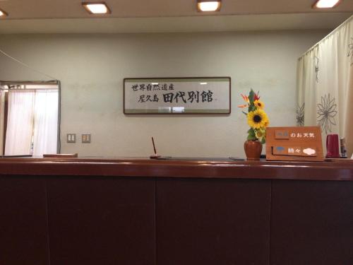 a reception counter with a vase of flowers on it at Tashiro Annex in Yakushima