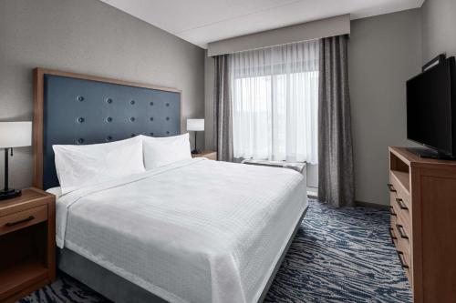 a hotel room with a bed and a flat screen tv at Homewood Suites by Hilton Boston Woburn in Woburn