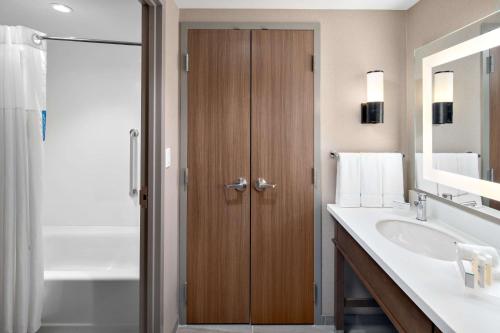a bathroom with a sink and a wooden door at Homewood Suites by Hilton Boston Woburn in Woburn