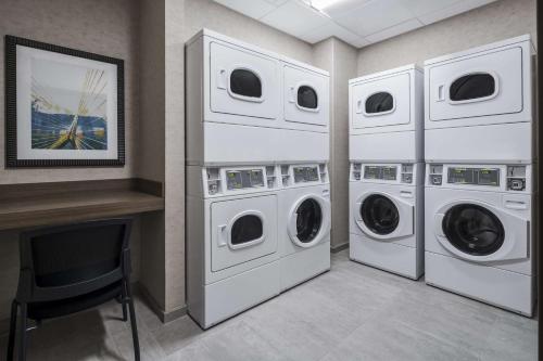 a laundry room with three washing machines and a fireplace at Homewood Suites by Hilton Boston Woburn in Woburn