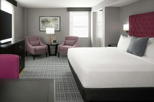 um quarto de hotel com uma cama grande e duas cadeiras em The Axis Moline Hotel, Tapestry Collection By Hilton em Moline