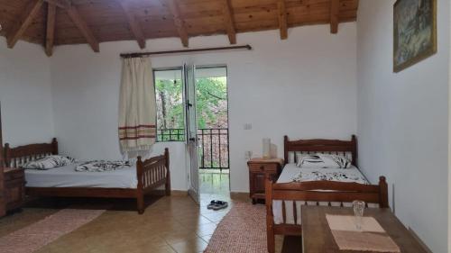 1 dormitorio con 2 camas, mesa y ventana en Bujtina Te Grima, en Theth