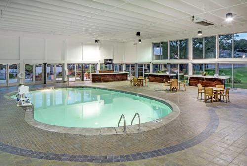 ein großer Pool in einem Gebäude mit Tischen und Stühlen in der Unterkunft Doubletree By Hilton Omaha Southwest, Ne in Omaha