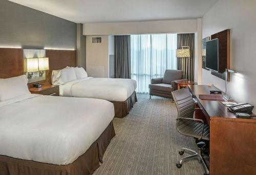 ein Hotelzimmer mit zwei Betten und einem Schreibtisch in der Unterkunft Doubletree By Hilton Omaha Southwest, Ne in Omaha