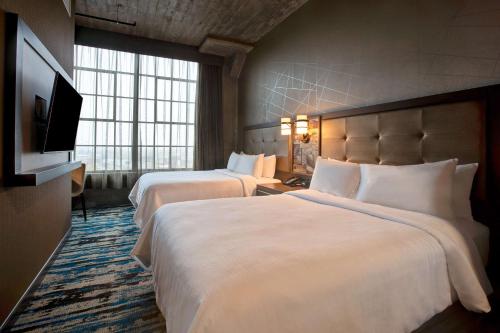 a hotel room with two beds and a flat screen tv at Embassy Suites By Hilton Rockford Riverfront in Rockford