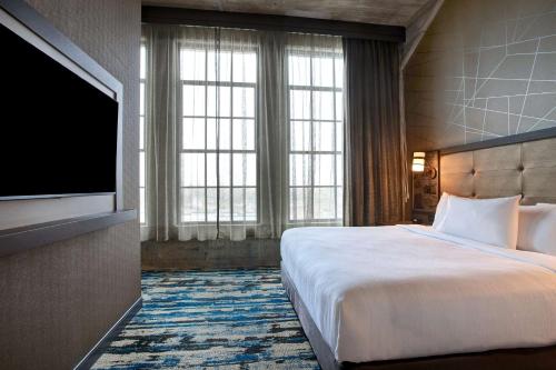 a hotel room with a bed and a flat screen tv at Embassy Suites By Hilton Rockford Riverfront in Rockford