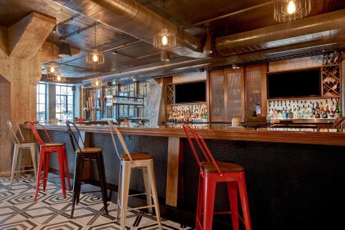 a bar with four red stools in a room at Embassy Suites By Hilton Rockford Riverfront in Rockford