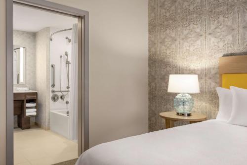 a bedroom with a bed and a bathroom with a shower at Home2 Suites By Hilton Glen Mills Chadds Ford in Glen Mills