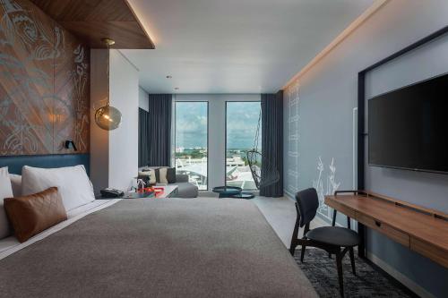 um quarto de hotel com televisão e sala de estar em Canopy By Hilton Cancun La Isla em Cancún