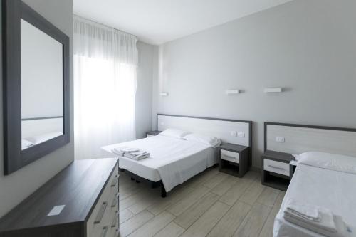 a white bedroom with a bed and a mirror at Residence Conchiglie in Marina Romea