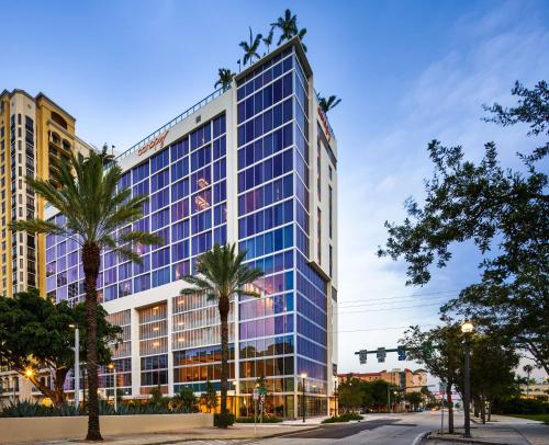 a tall building with palm trees in front of a street at Canopy West Palm Beach - Downtown in West Palm Beach