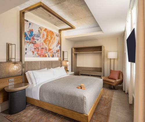 a hotel room with a bed and a chair at Canopy West Palm Beach - Downtown in West Palm Beach