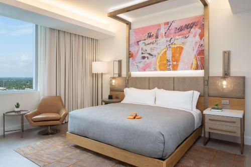 a hotel room with a bed and a chair at Canopy West Palm Beach - Downtown in West Palm Beach