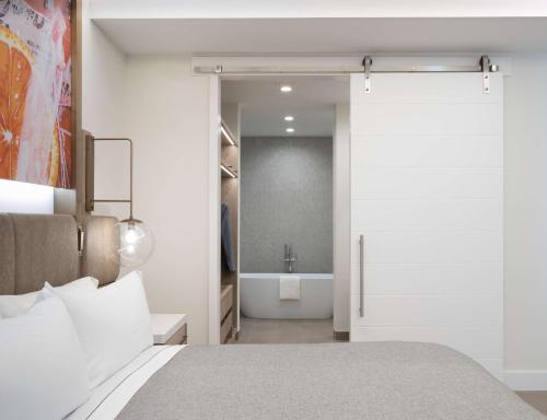 a bedroom with a bed and a bathroom with a tub at Canopy West Palm Beach - Downtown in West Palm Beach