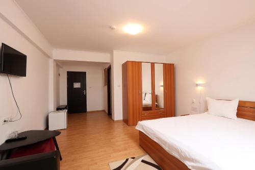 a bedroom with a bed and a desk and a television at Pensiunea Cavaler in Baile Felix