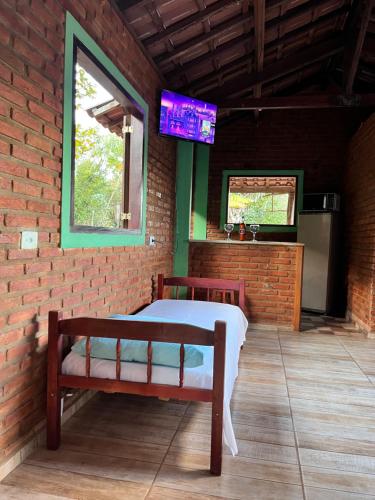 ein Schlafzimmer mit einem Bett und einem TV an einer Backsteinwand in der Unterkunft Sítio do pica pau amarelo in São Thomé das Letras