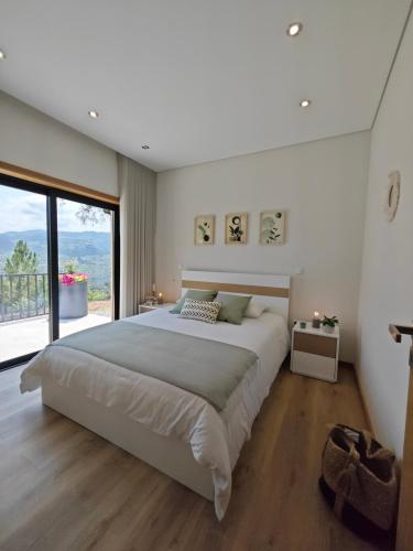 a bedroom with a large bed and a large window at Casa da Milinha - Villa with a Pool near Rio Douro in Santa Cruz do Douro