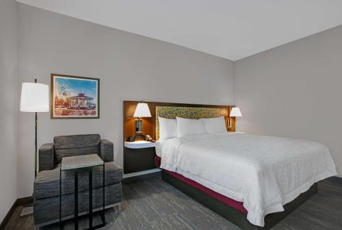 a hotel room with a bed and a chair at Hampton Inn & Suites Farmers Branch Dallas, Tx in Farmers Branch