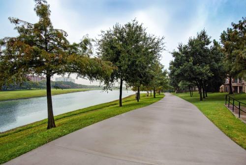 a walkway through a park next to a river at Hampton Inn & Suites Dallas - Farmers Branch in Farmers Branch