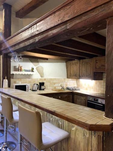 une cuisine avec un comptoir en bois et des chaises dans l'établissement L'atypique, bord du Thiou, à Annecy