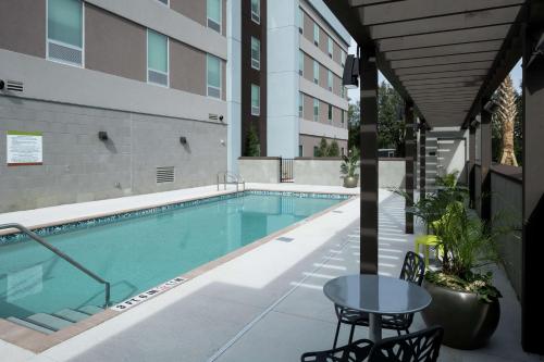 a swimming pool with a table next to a building at Home2 Suites By Hilton Jacksonville Airport in Jacksonville