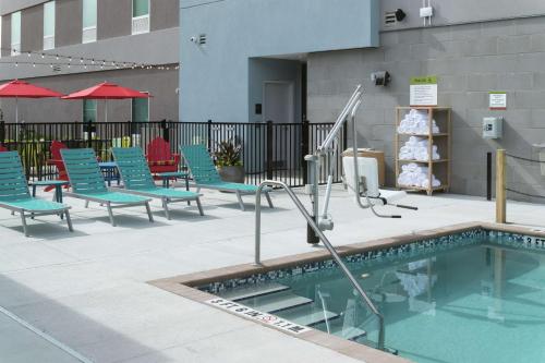 a swimming pool with blue chairs and a group at Home2 Suites By Hilton Jacksonville Airport in Jacksonville