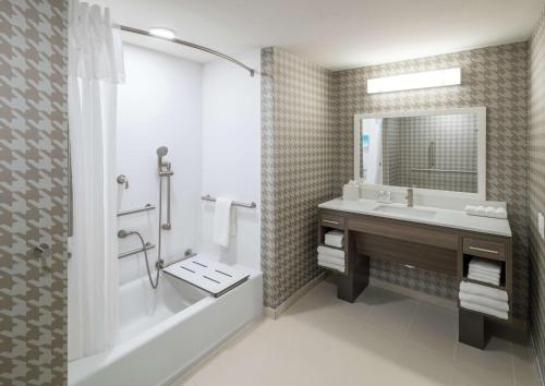 Home2 Suites By Hilton Jacksonville Airport في جاكسونفيل: حمام مع حوض ومغسلة ودش