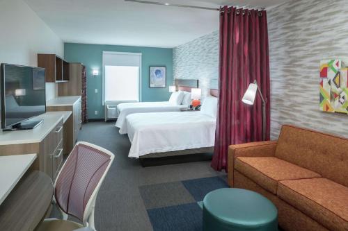 a hotel room with a bed and a couch at Home2 Suites By Hilton Jacksonville Airport in Jacksonville