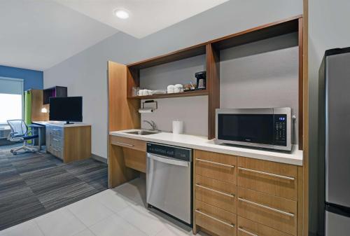 a kitchen with a sink and a microwave at Home2 Suites by Hilton Liberty NE Kansas City, MO in Liberty