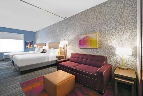 リバティにあるHome2 Suites by Hilton Liberty NE Kansas City, MOのベッドとソファ付きのホテルルーム