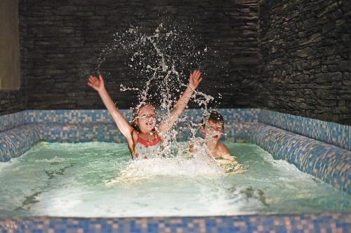 dwoje dzieci bawi się w basenie w obiekcie Hotel Vydrovy Boudy w mieście Pec pod Sněžkou