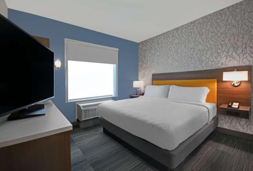 a bedroom with a bed and a flat screen tv at Home2 Suites by Hilton Liberty NE Kansas City, MO in Liberty