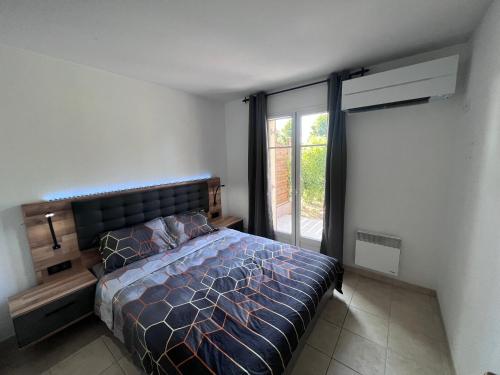 ein Schlafzimmer mit einem Bett und einem großen Fenster in der Unterkunft Appartement T2 avec jardin privé, piscine et barbecue in Lorgues