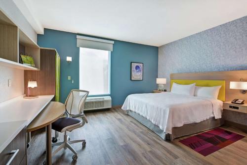 西棕榈滩Home2 Suites By Hilton West Palm Beach Airport的配有床、桌椅的酒店房间