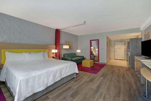 a hotel room with a large bed and a television at Home2 Suites By Hilton West Palm Beach Airport in West Palm Beach