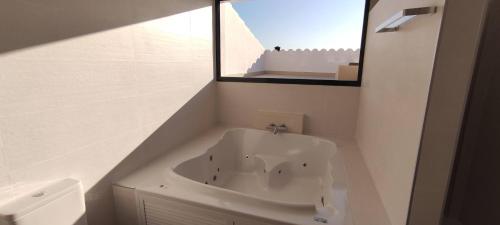 La salle de bains est pourvue d'une baignoire blanche et d'un miroir. dans l'établissement Casa Rural Reserva de las Nieves, à Tolox