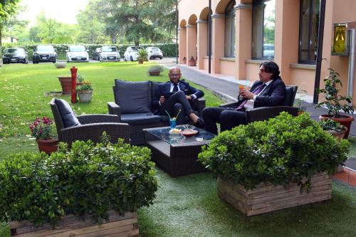two people sitting on couches on a patio at Hotel Le Ville in Modena