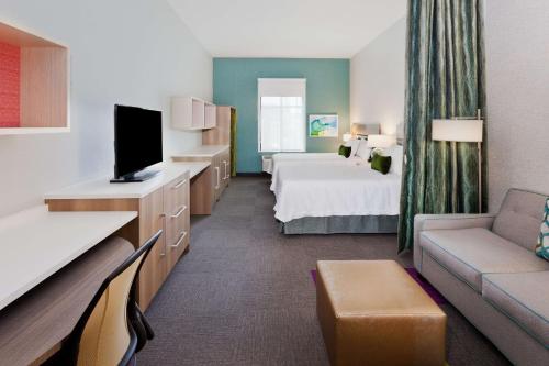 a hotel room with a bed and a couch at Home2 Suites By Hilton Alpharetta, Ga in Alpharetta