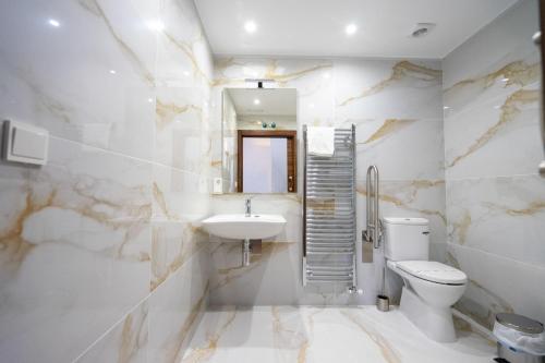 une salle de bain avec un lavabo, des toilettes et un miroir dans l'établissement alojamiento cuatro estaciones, à La Pola de Gordón