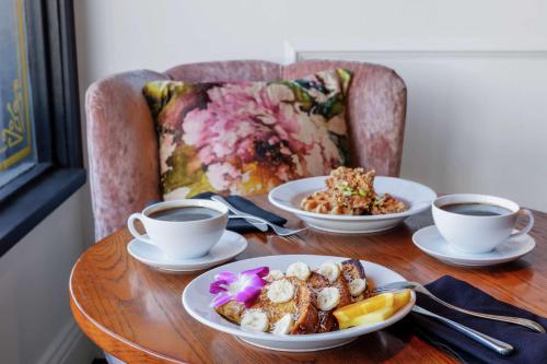 a table with plates of food and two cups of coffee at The Fin Hotel, Tapestry Collection by Hilton in Oceanside