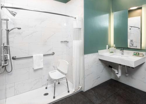 y baño con ducha, lavabo y silla. en The Fin Hotel, Tapestry Collection by Hilton, en Oceanside