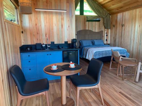um quarto com uma cama, uma mesa e cadeiras em Refúgio de Altitude - Centro em Urupema