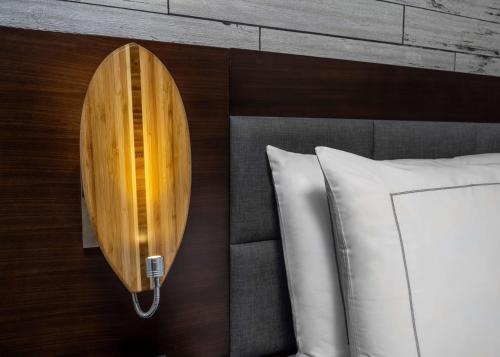 a wooden surfboard on a wall next to a bed at The Fin Hotel, Tapestry Collection by Hilton in Oceanside
