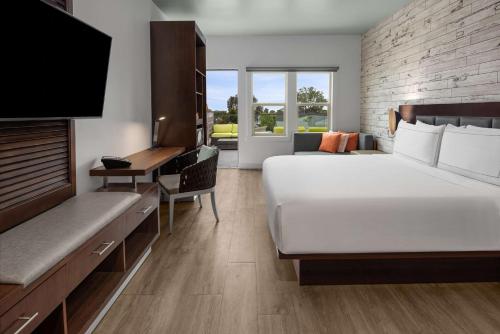 a hotel room with a large bed and a desk at The Fin Hotel, Tapestry Collection by Hilton in Oceanside